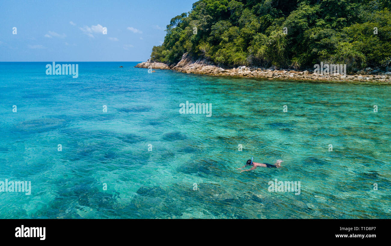 Man snorkeling alone in a tropical sea over coral reef with clear blue crystalline water. Perhentian Island, Malaysia Stock Photo