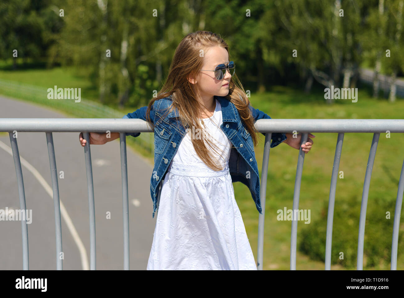 portrait of beautiful little girl in white dress in blue denim jacket and sunglasses. fashion, kid model Stock Photo