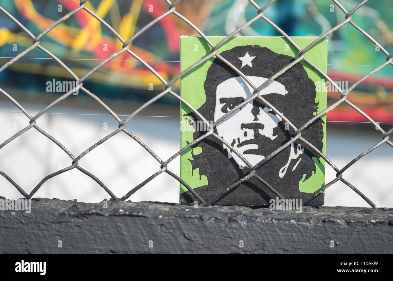 A small painting of Ché Guevara sits behind a chainlink fence. He was known as one of the guerrilla leaders during the Cuban revolution. Stock Photo