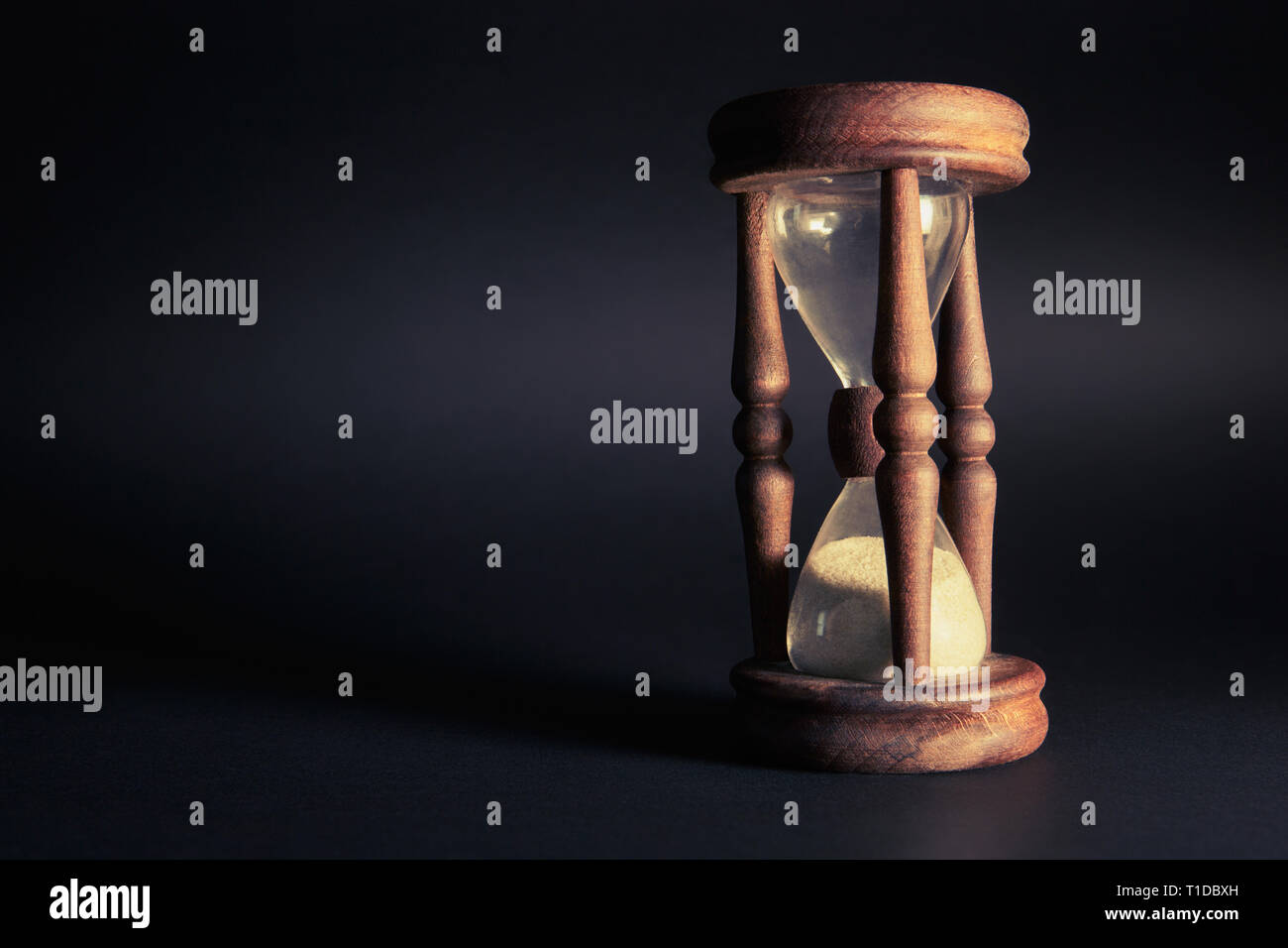 sand clock on a black background with long shadows Stock Photo