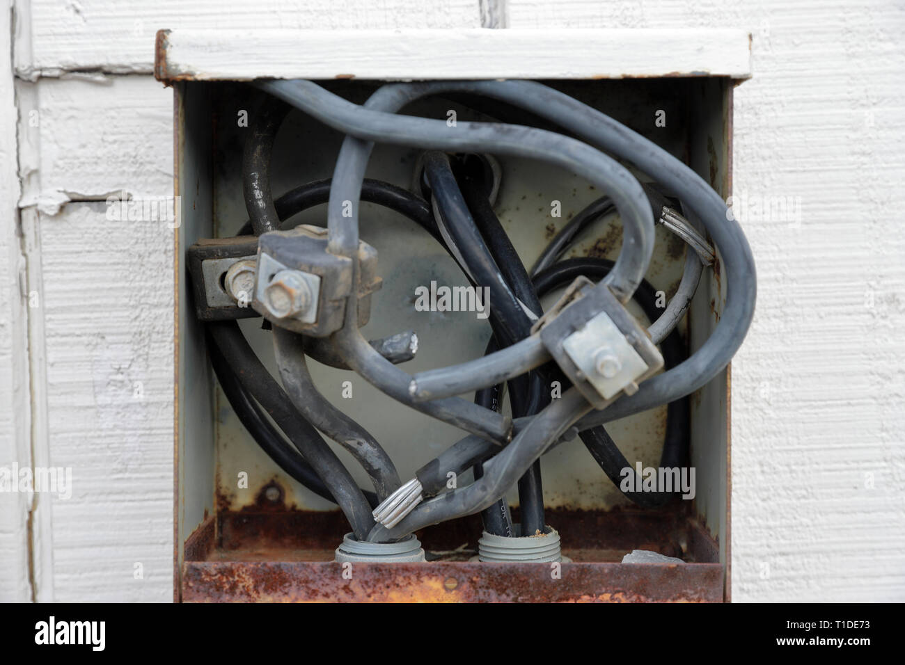 Old electrical connection panel or box on outside of building, wires exposed Stock Photo