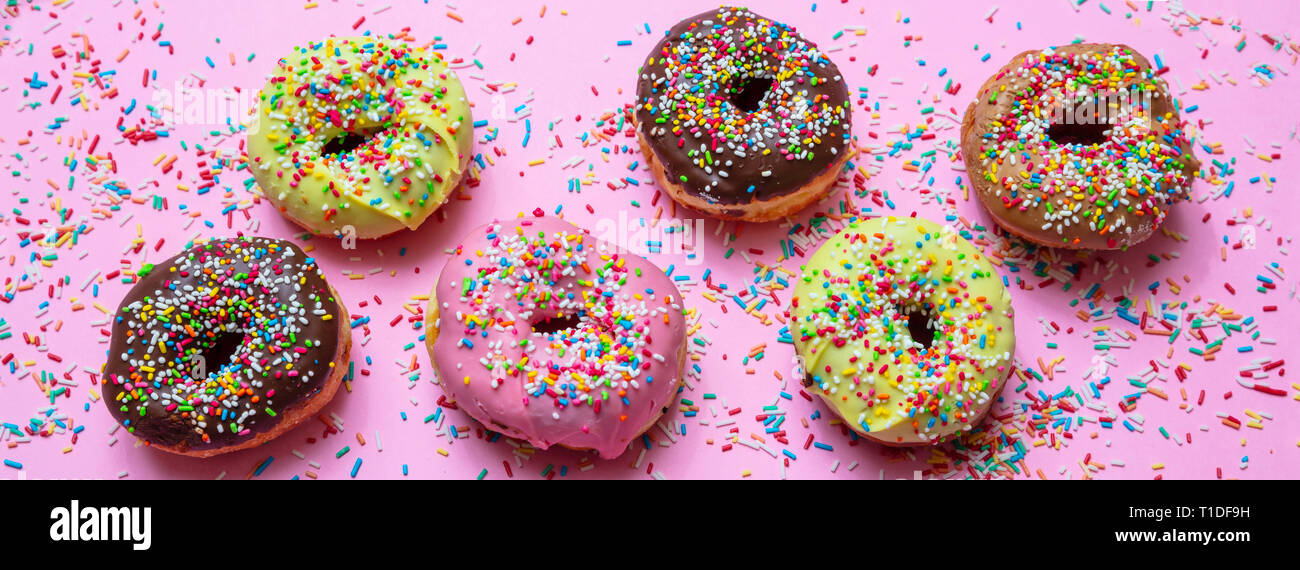 Donuts assorted. Doughnuts with colorful sprinkles and icing on pink ...