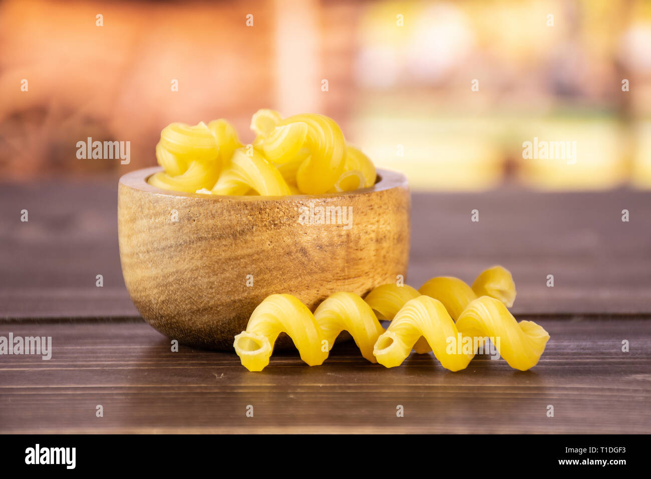 Lot of whole raw pasta cavatappi with wooden bowl with cart in background Stock Photo Alamy