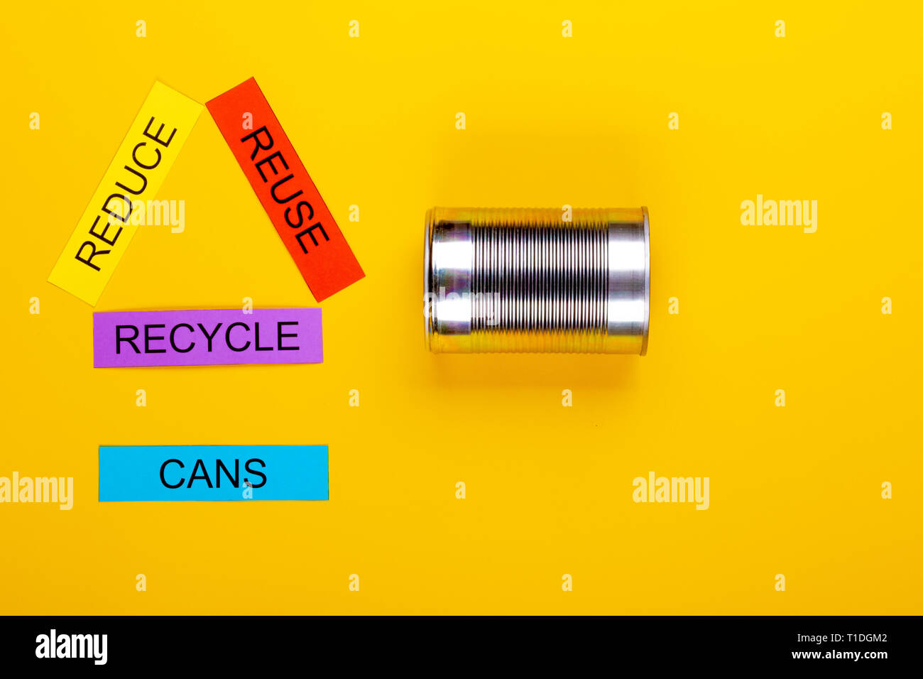 Recycling concept showing reduce, reuse & recycle with cans on a yellow ...