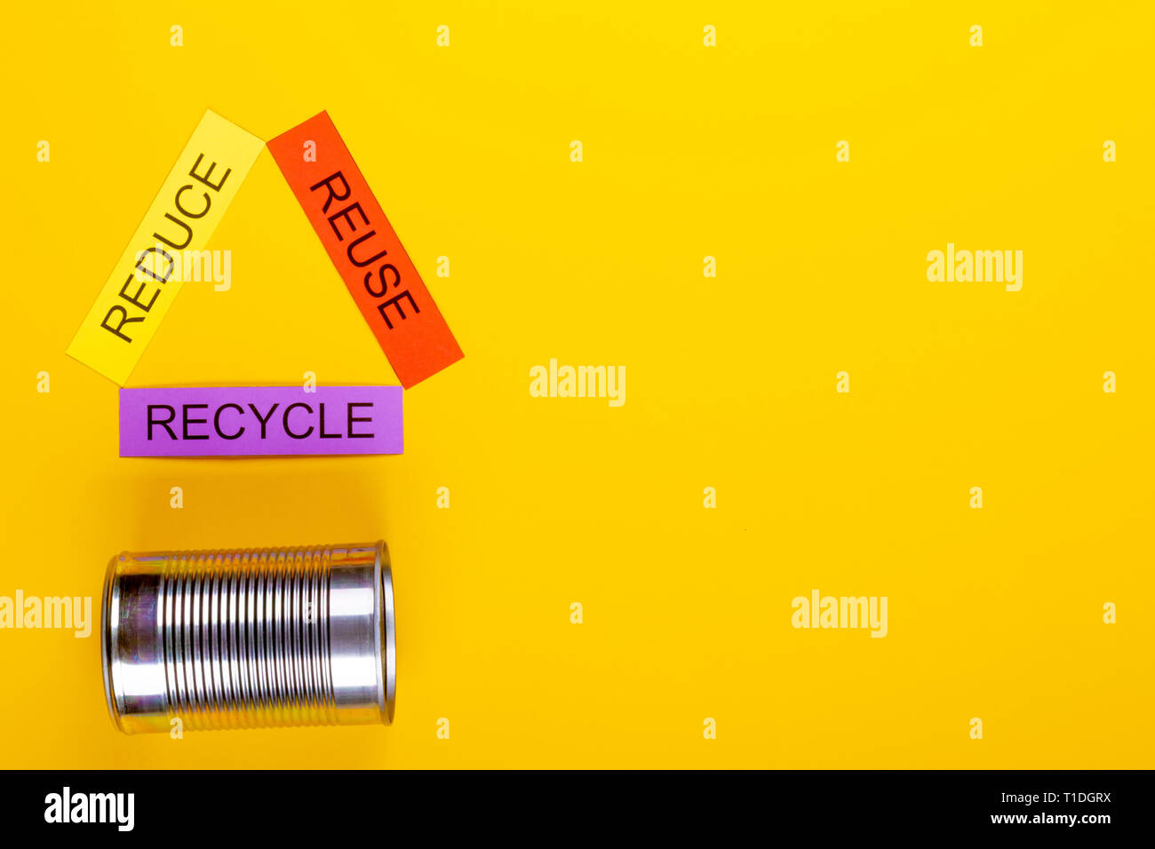 Recycling concept showing reduce, reuse & recycle with cans on a yellow ...