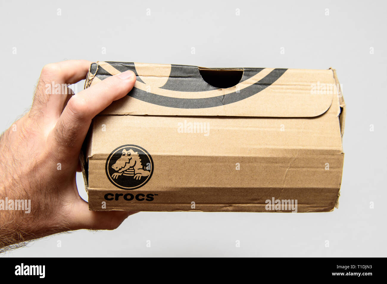 Paris, France - Jun 12, 2018: Freshly delivered Crocs shoes cardboard box featuring big crocodile logotype side view of the damaged cardboard box Stock Photo