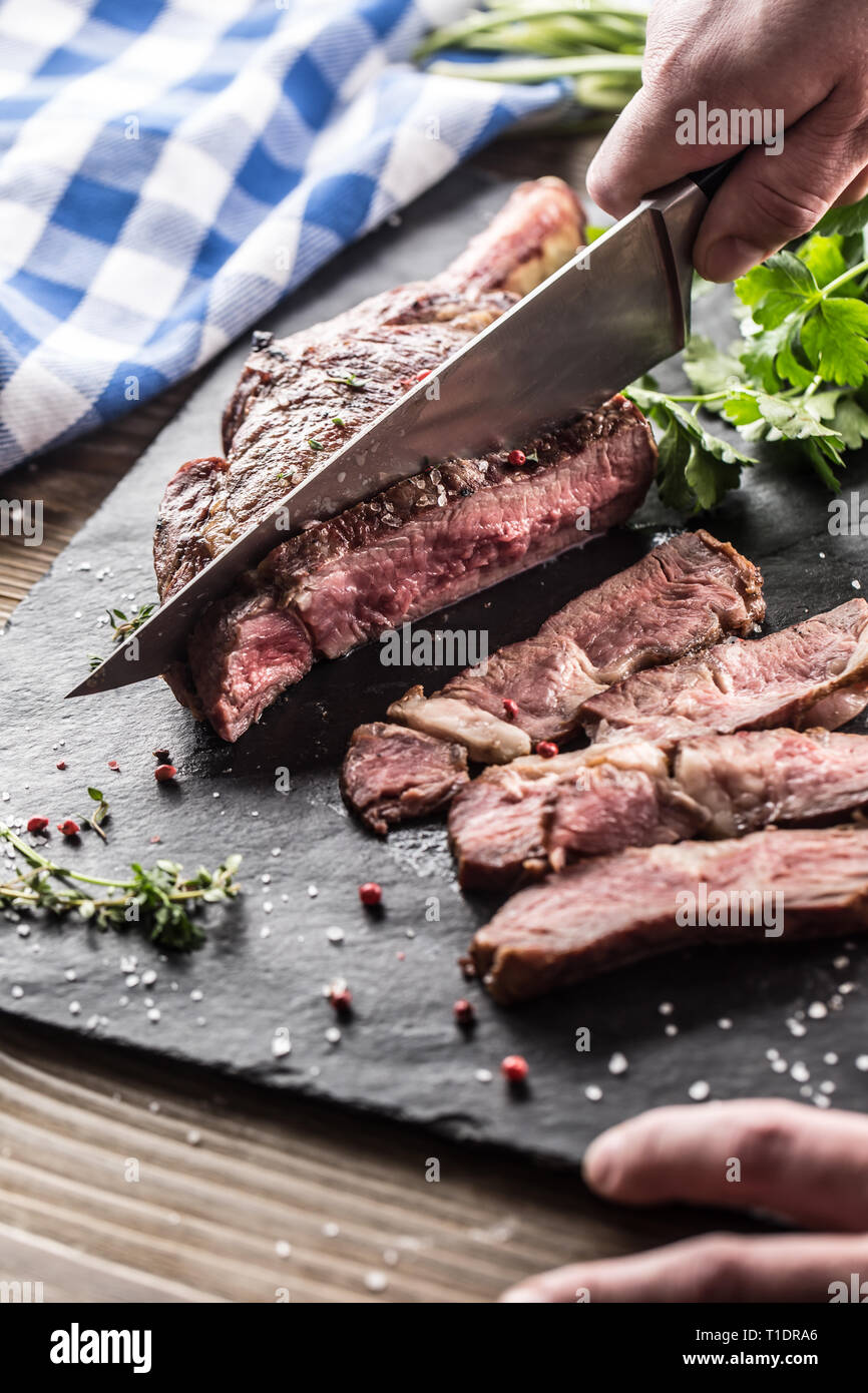 https://c8.alamy.com/comp/T1DRA6/freshly-grilled-tomahawk-steak-on-slate-plate-with-salt-pepper-rosemary-and-parsley-herbs-chef-with-knife-cuts-juicy-bovine-steak-T1DRA6.jpg