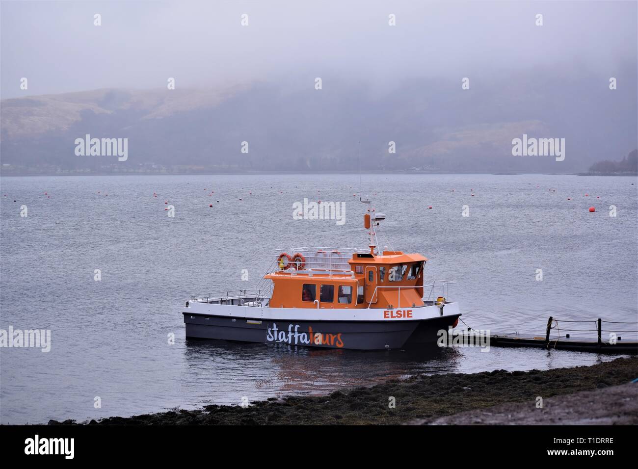 Staffa Tours Boat Elsie at anchor on Loch Creran shore in mist opposite the Fish Farm Hatchery. A sense of lonely isolation in the so misty sea loch. Stock Photo