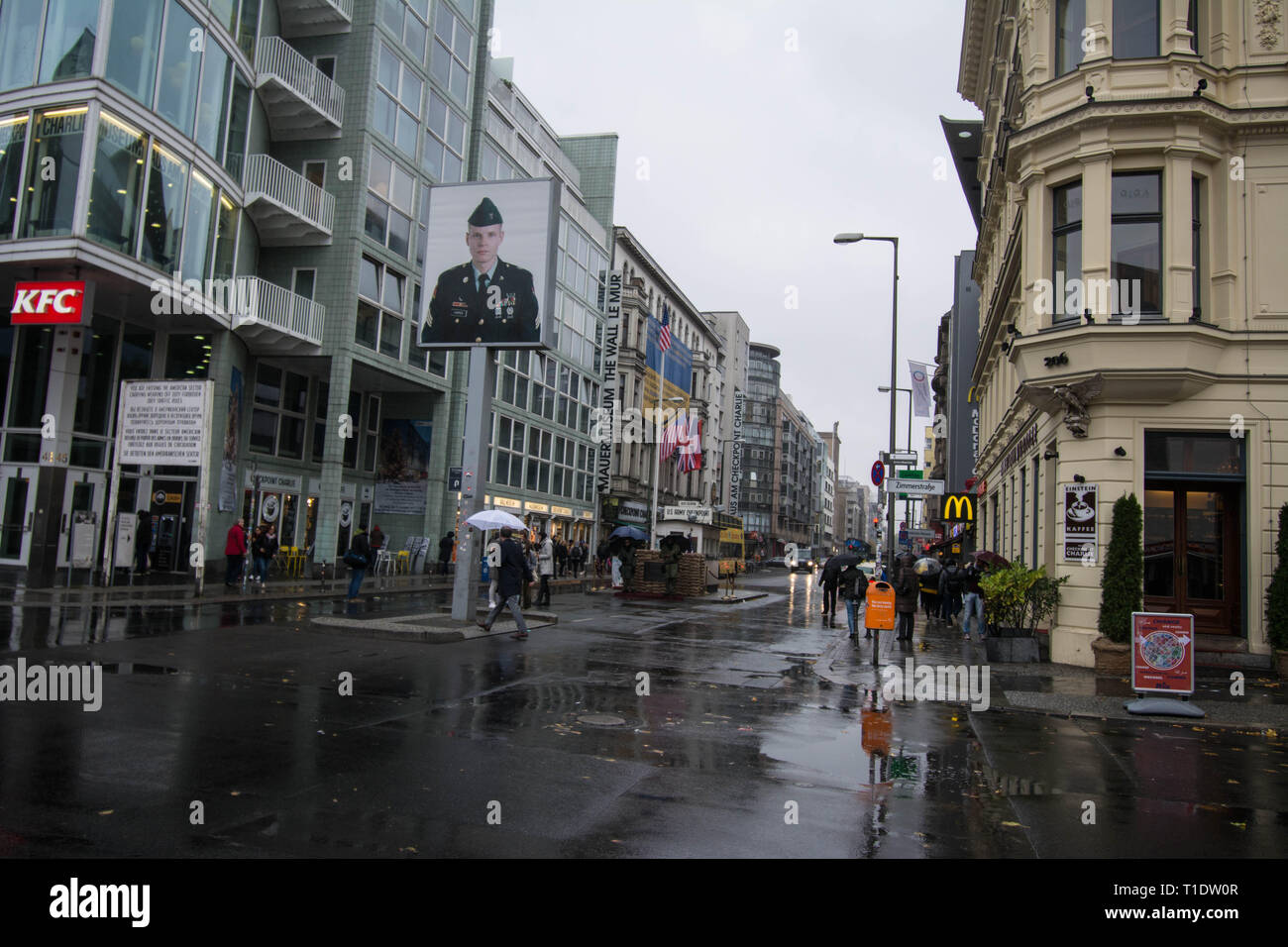 People with umbrellas in the rain at Check point Charlie in Berlin