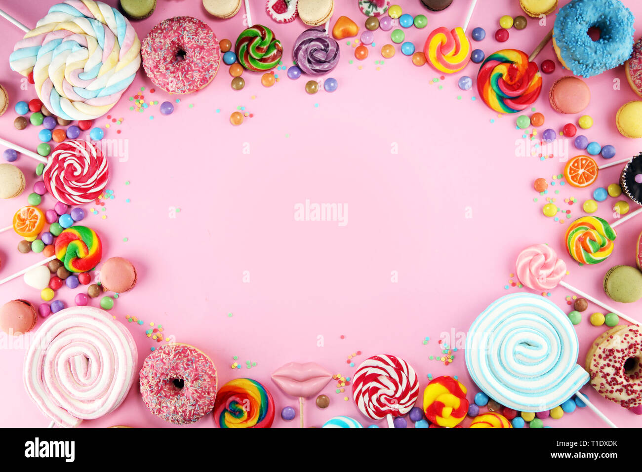 candies with jelly and sugar. colorful array of different childs sweets and treats on pink background Stock Photo
