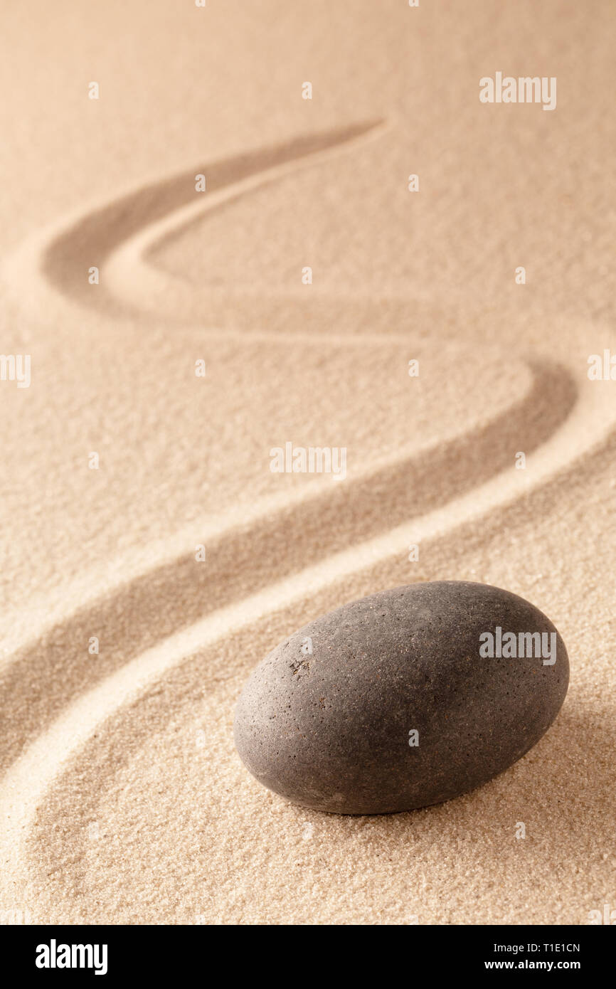black round zen meditation stone for focus and concentration in Japanese sand garden. Textured background with copy space for mindfulness or spa welln Stock Photo