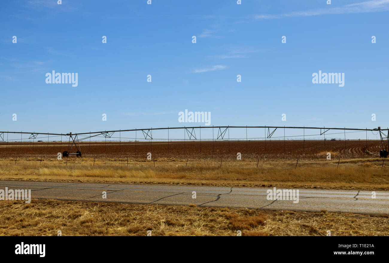 An irrigation pivot watering a field system in function watering agricultural plants Stock Photo