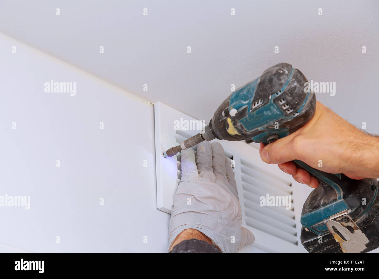 Man is holding hand drill in hands. Worker installing the wall bathroom vent restoration process repair works renovation in the flat. Stock Photo