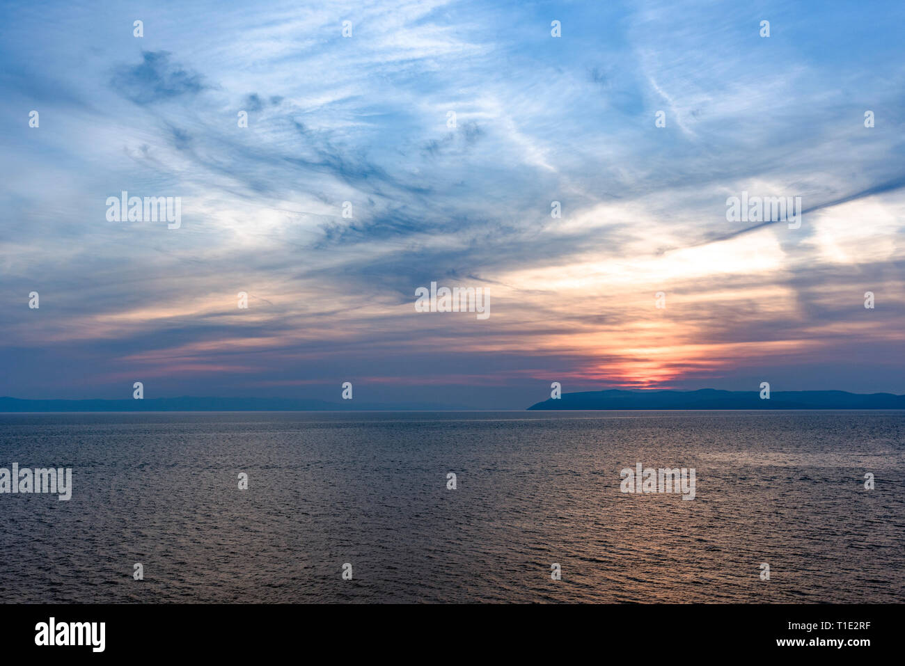 Sunset over the sea with mysterious sky with reflection in the water ...