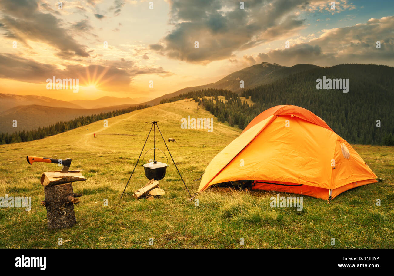 Orange tent with a prepared bonfire at sunset Stock Photo