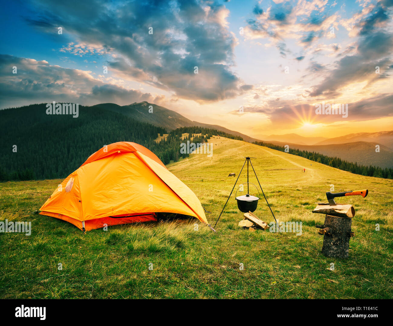 Tourist camp in mountains with tent and cauldron over fire at sunset Stock Photo