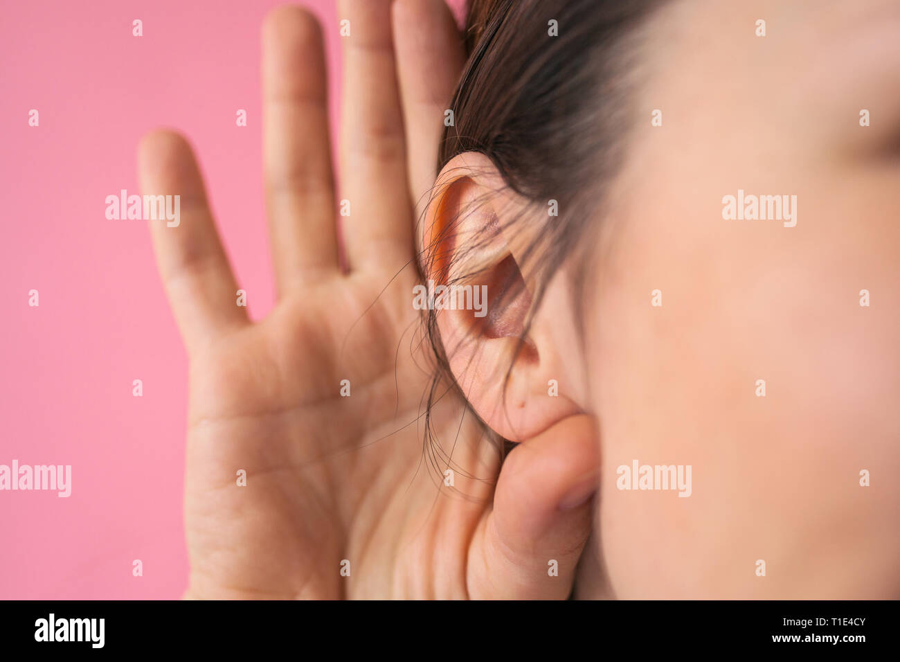 Close-up of a girl holding her hand next to her ear. The concept of chatter, gossip, news or secrets. Stock Photo