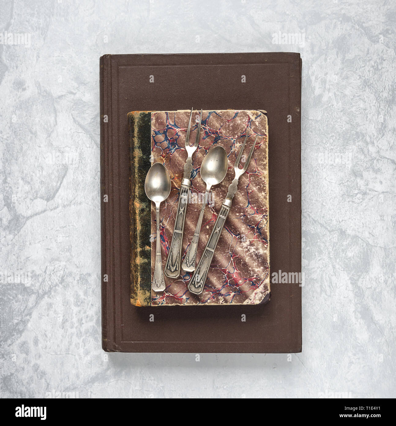 Antique teaspoons and dessert forks are on an old books Stock Photo