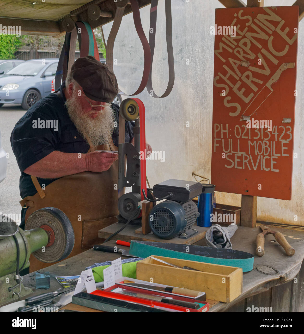 A knife sharpener tradesman at work at the Matakana Farmers Market, Matakana, New Zealand. Stock Photo
