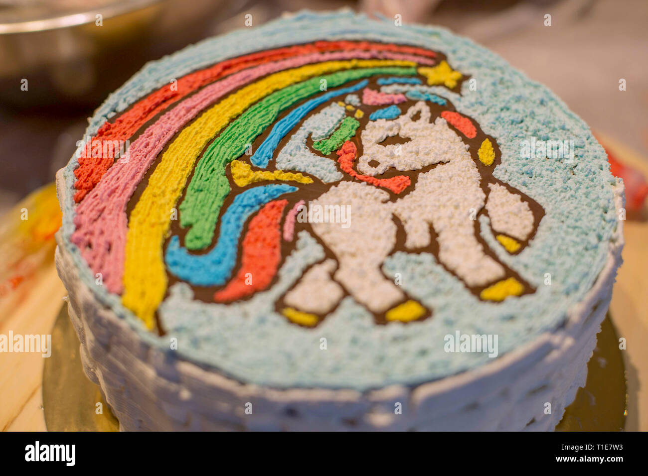 Decorating a birthday cake with icing sugar unicorn Stock Photo - Alamy