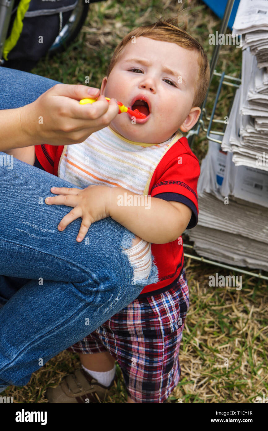 Miami Florida,Kendall,Tropical Parkboy,boys kid kids child children,male,toddler,toddlers,child,feeding,eat,being fed,bib,mouth open,visitors travel t Stock Photo