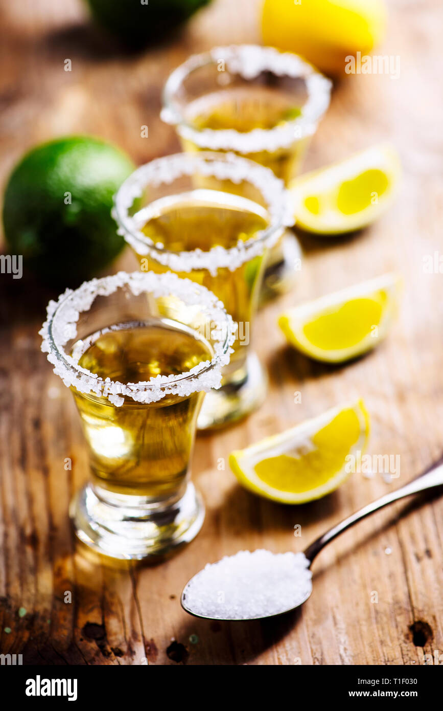 Golden mexican tequila in shot glass with lime and salt on vintage
