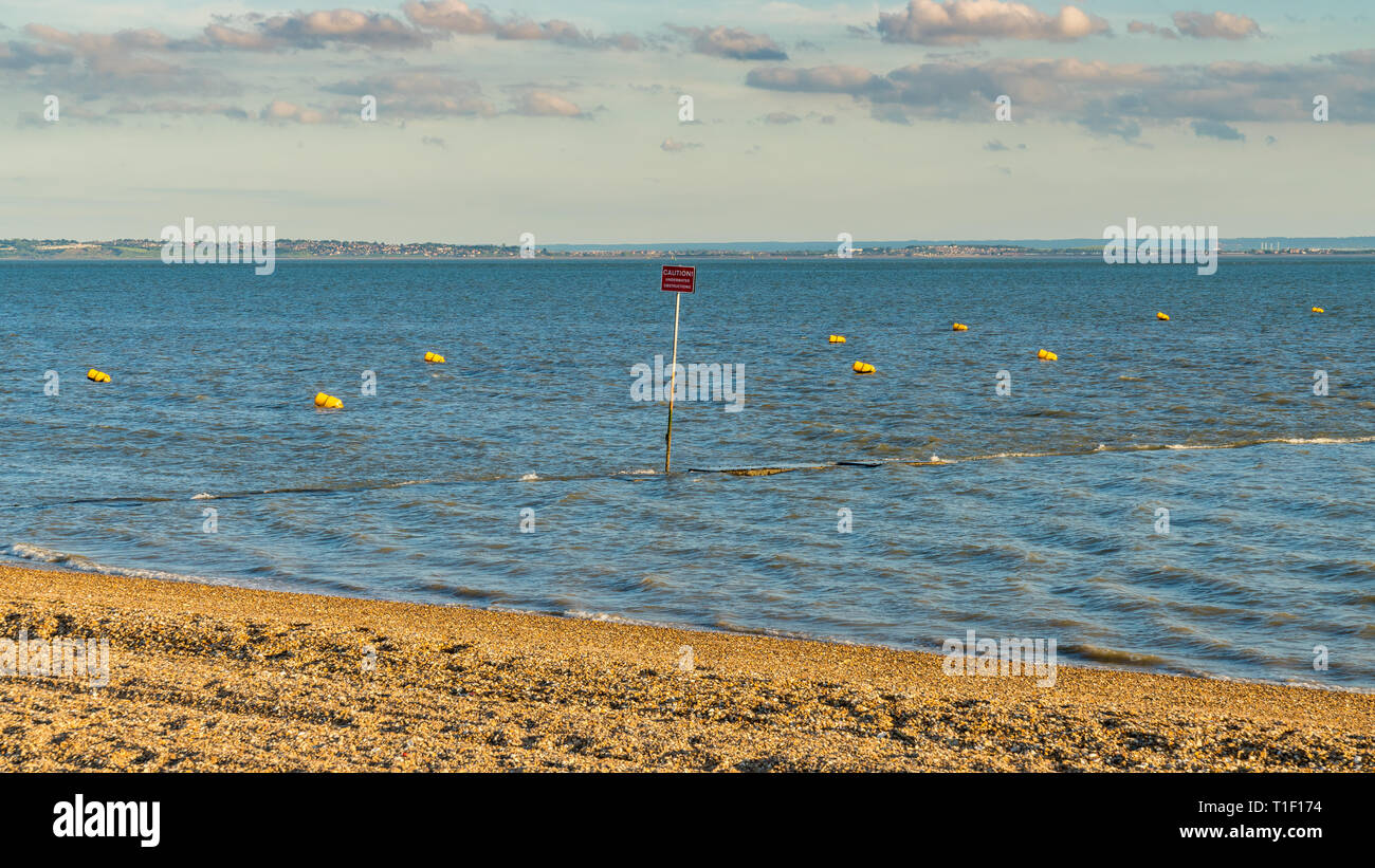 Buoys and a warning sign on the shore of the River Thames, seen in