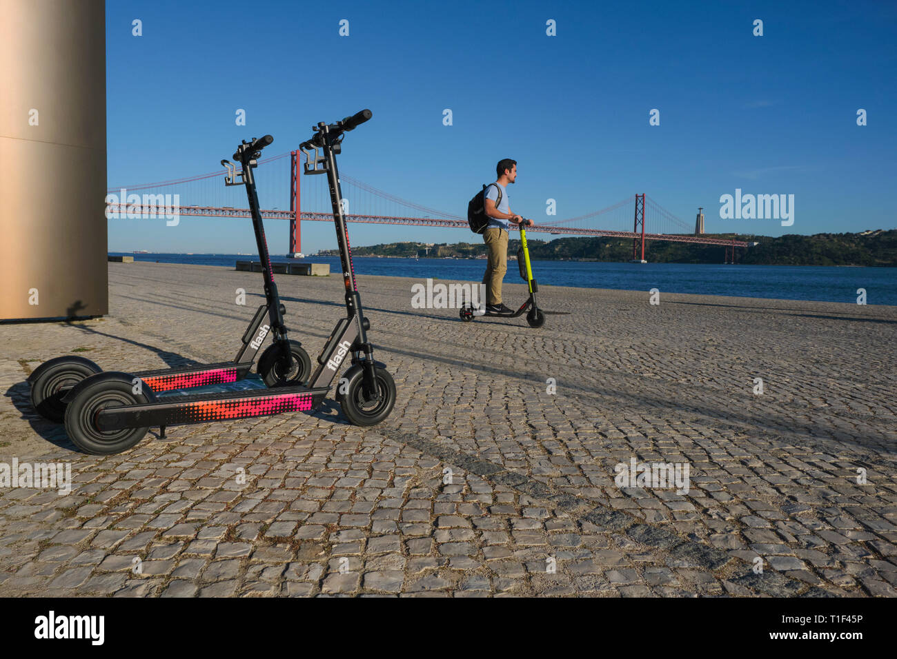 Riding electric scooter along river Tejo in Lisbon Stock Photo