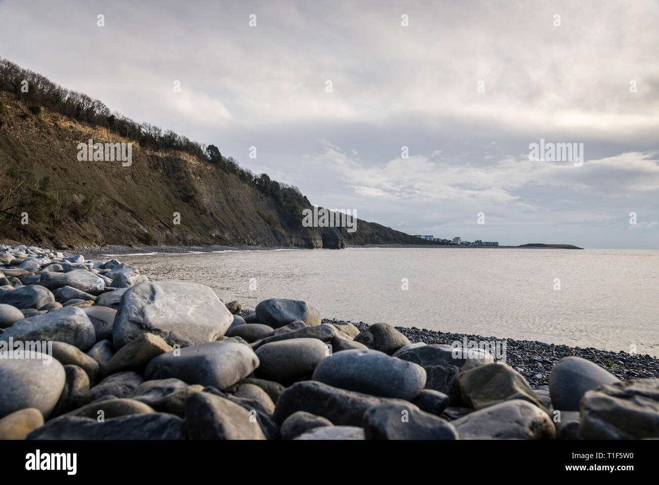 A low level view the steep cliffs and pebble beach between the Knap and Porthkerry, Barry, on an overcast, cloudy day Stock Photo