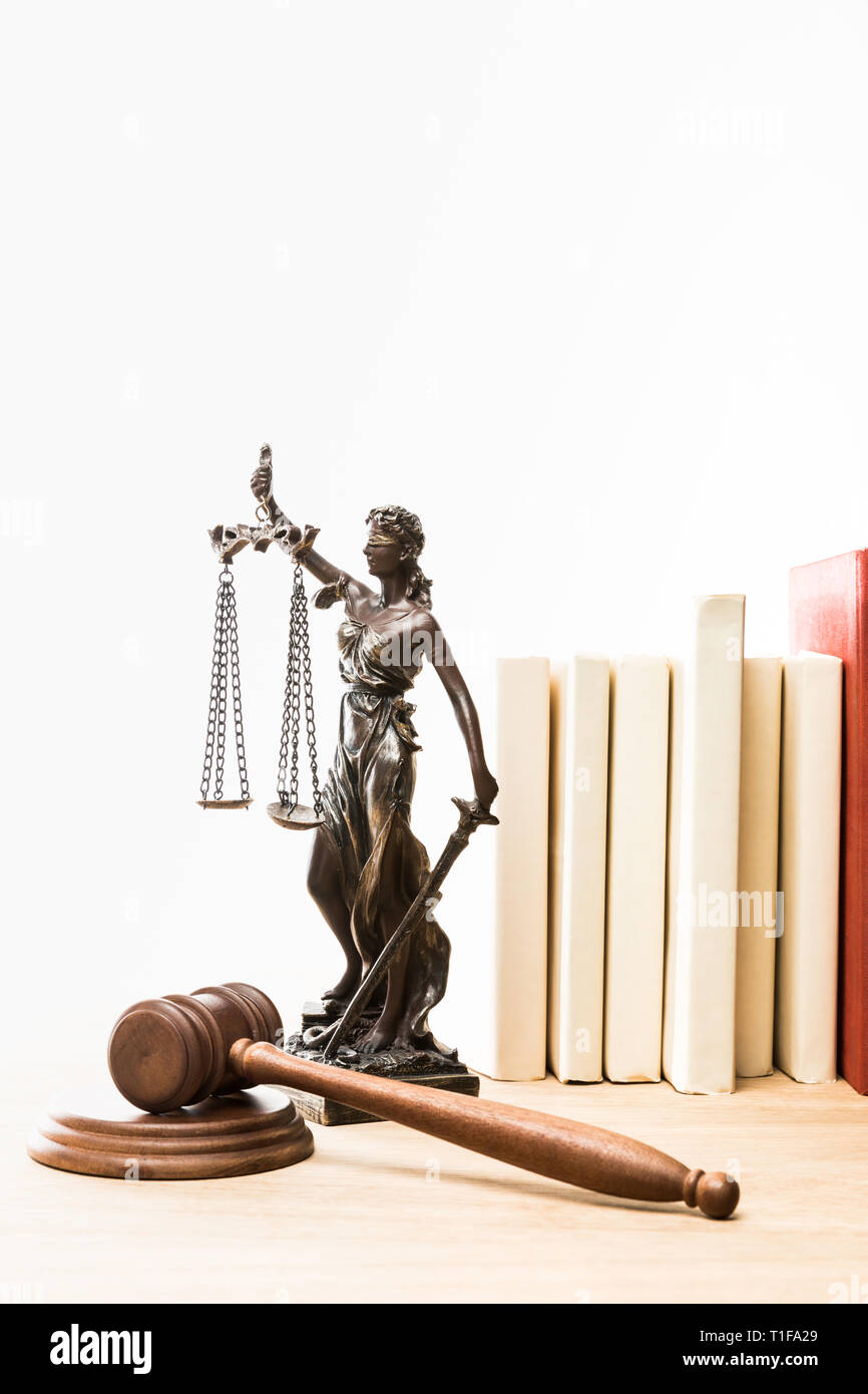metal figure with scales of justice, gavel and books on wooden table isolated on white Stock Photo