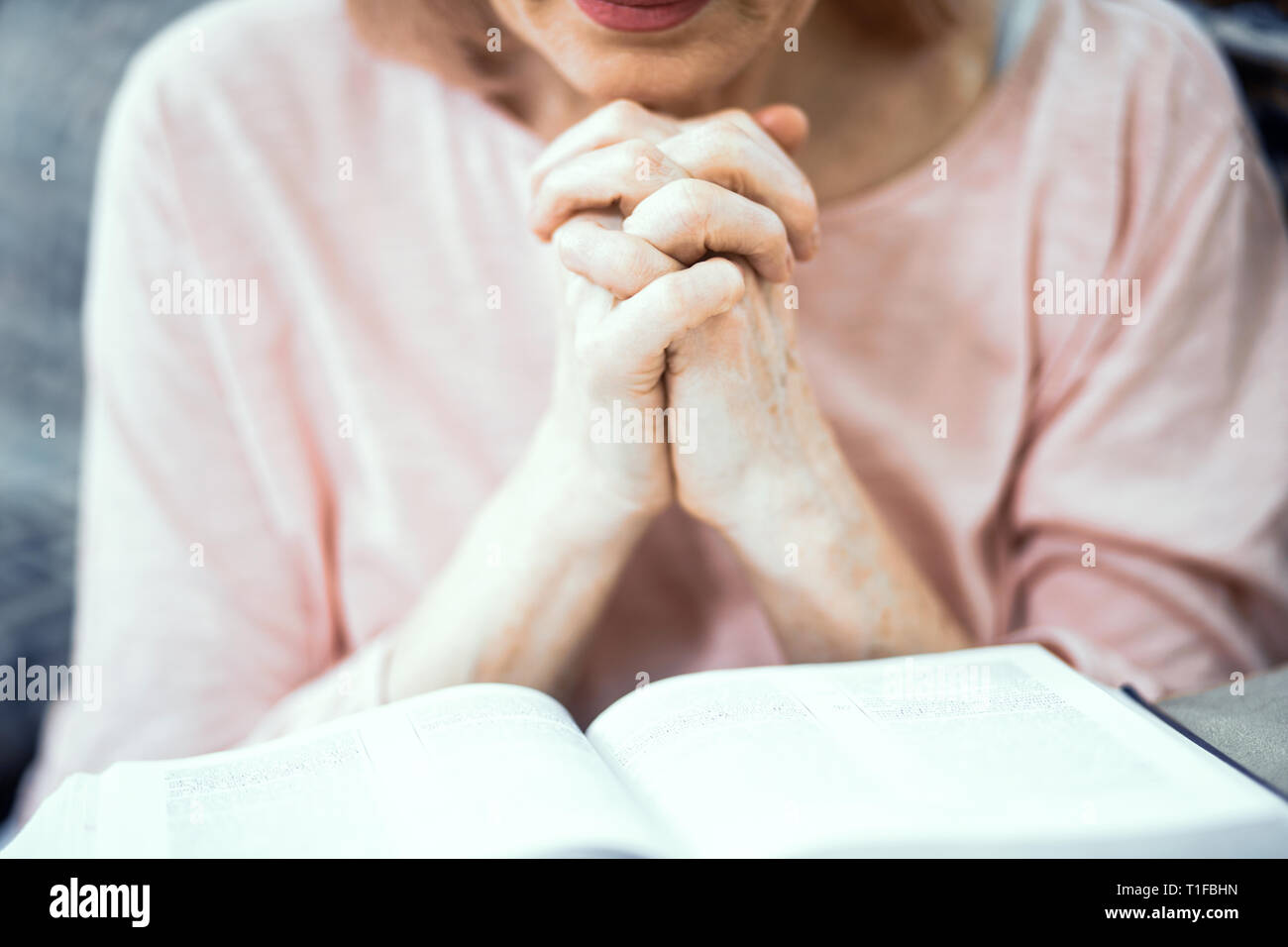 Middle Aged Woman Sitting On Sofa And Praying Stock Photo