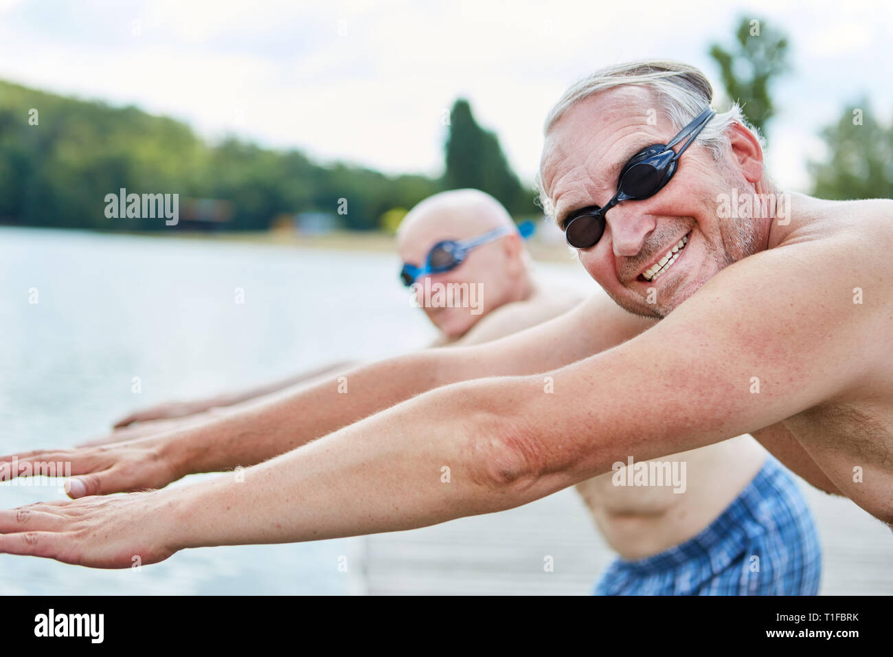 Two seniors with diving goggles go swimming and doing gymnastics Stock Photo