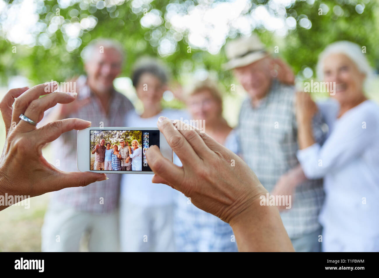 Person takes a photo of a senior citizen group on vacation with his smartphone Stock Photo