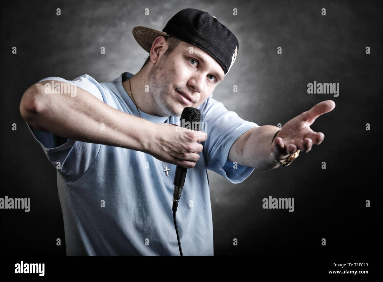 Rapper attitude rap singer hip Hop Dancer performing. Young man with microphone singing hand cool gesture black grunge background Stock Photo