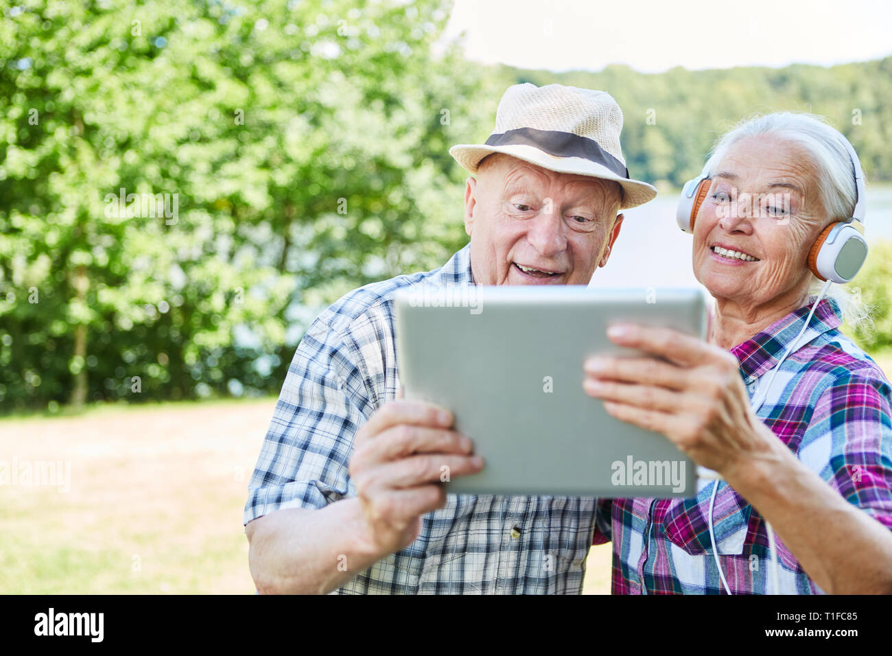 Senior couple on a nature trip with tablet computer and headphones Stock Photo