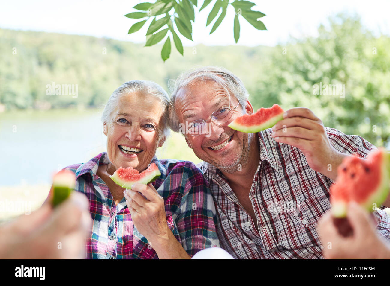 Happy couple of seniors eating melon together on a trip in the summer Stock Photo