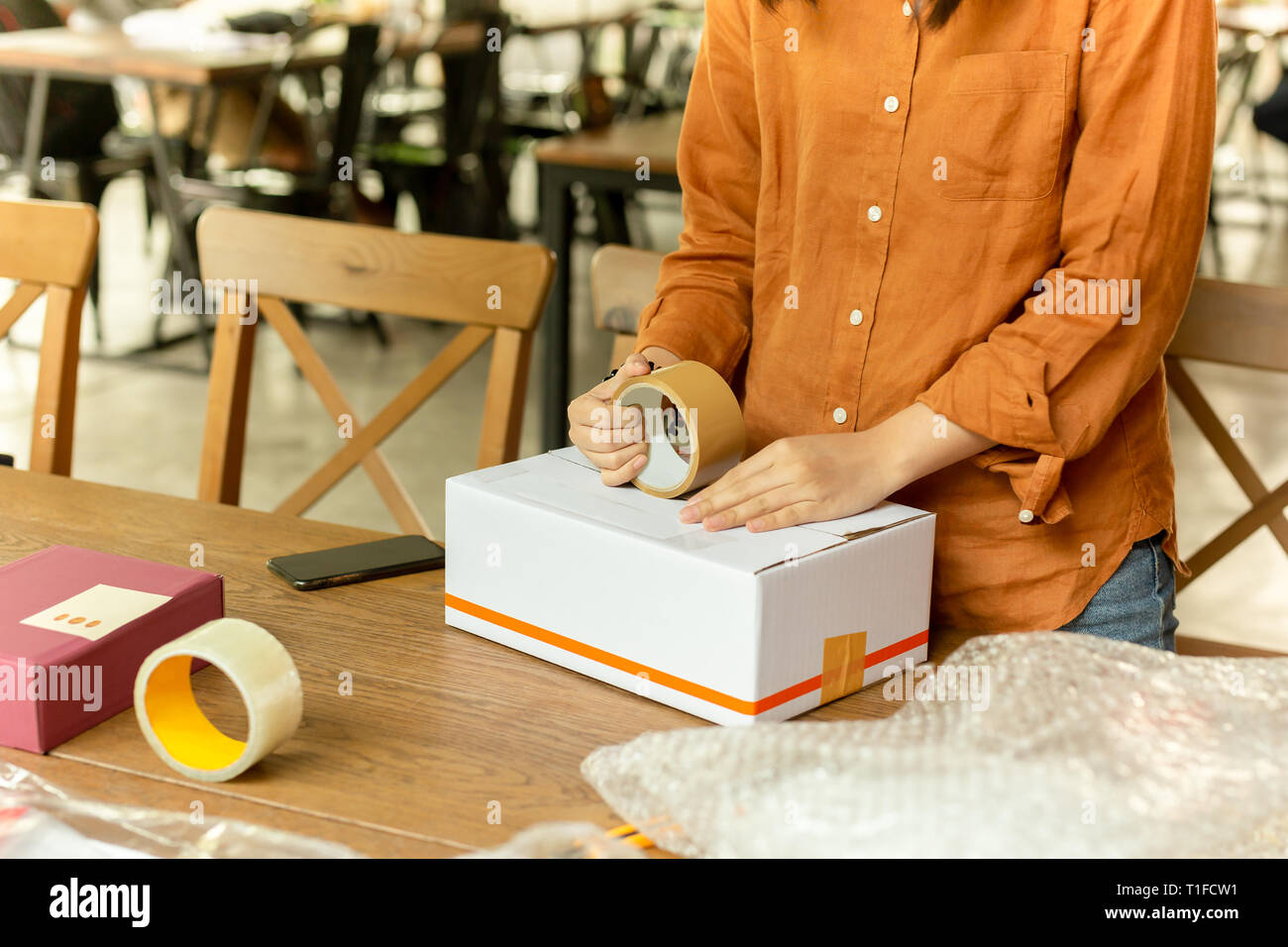 Startup small business woman owner packing cardboard box at workplace ...