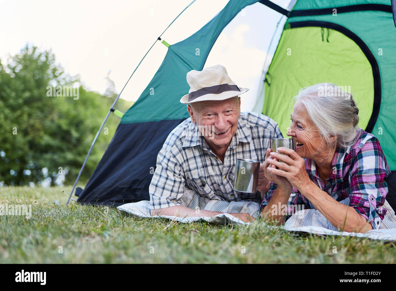 Happy couple seniors in the tent camping on a summer campsite Stock