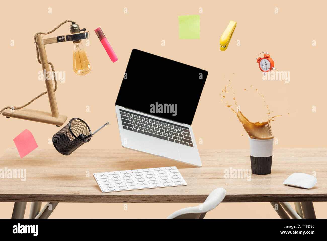 laptop with blank screen, lamp, empty sticky notes and stationery levitating in air above workplace with thermomug with coffee splash  on table isolat Stock Photo
