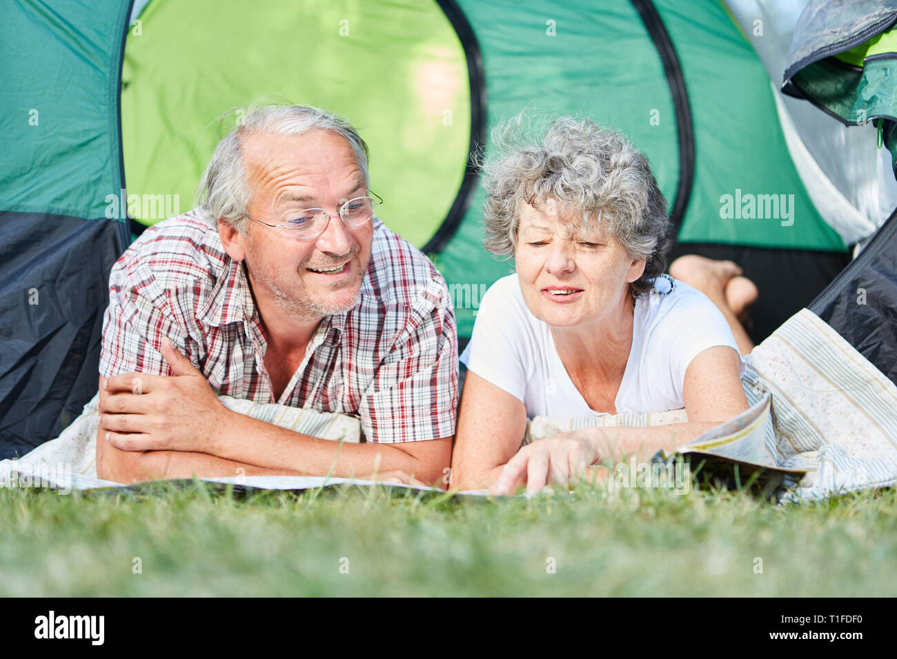 Senior couple lies relaxed in the tent on a camping holiday and plans a trip Stock Photo