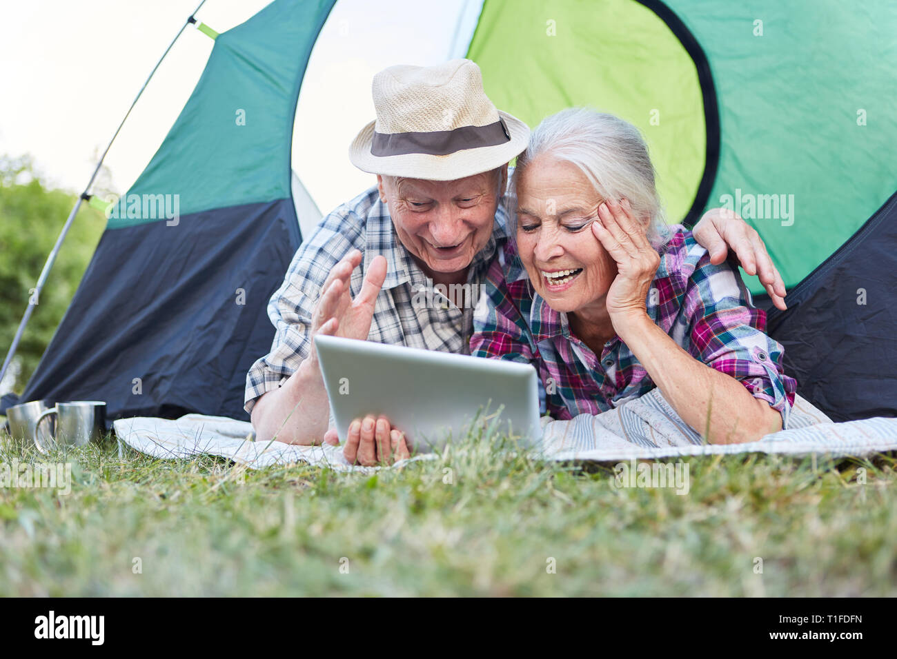 Senior couple having fun at the video chat online with the tablet computer while camping Stock Photo