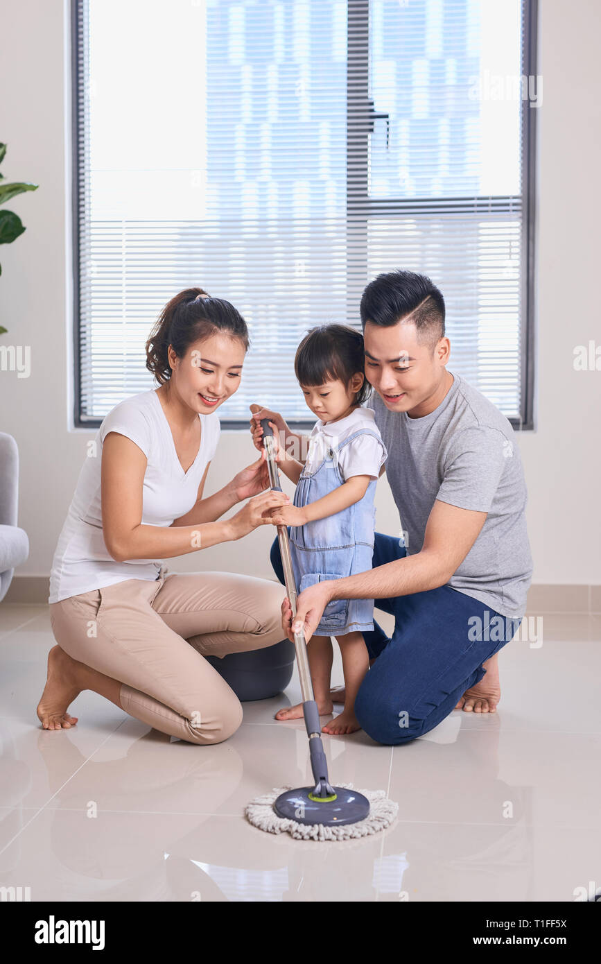 Ordinary family of three doing house cleaning with cleaning equipment Stock Photo