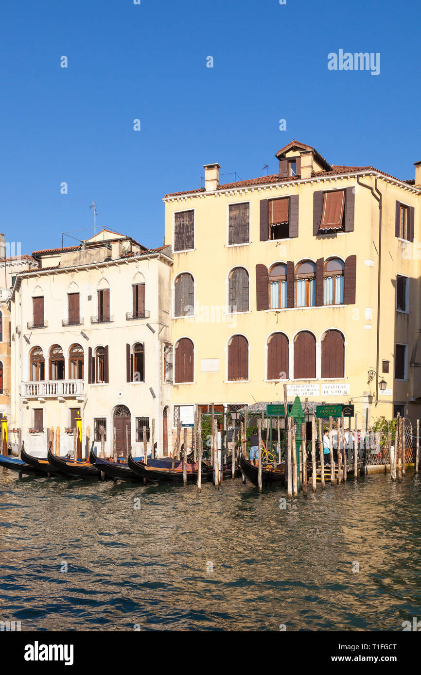 Gondola and traghetto station at San Toma, Grand Canal, San Polo, Venice, Veneto, Italy at sunrise, moored gondolas, people waiting to board traghetto Stock Photo