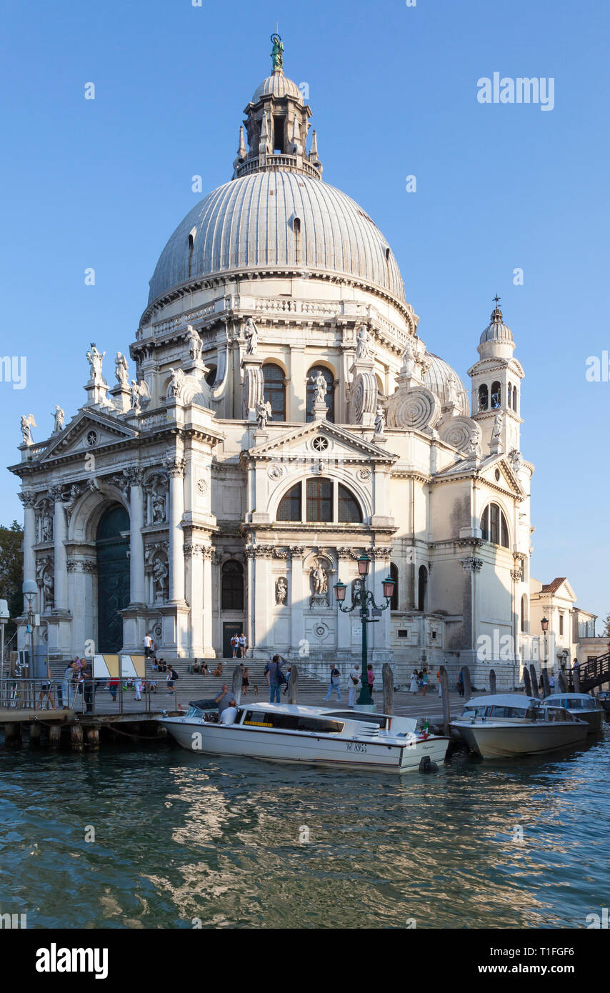 Basilica di Santa Maria della Salute at sunset from Grand Canal, Dorsoduro, Venice, Veneto, Italy with water taxis in the foreground and tourists Stock Photo