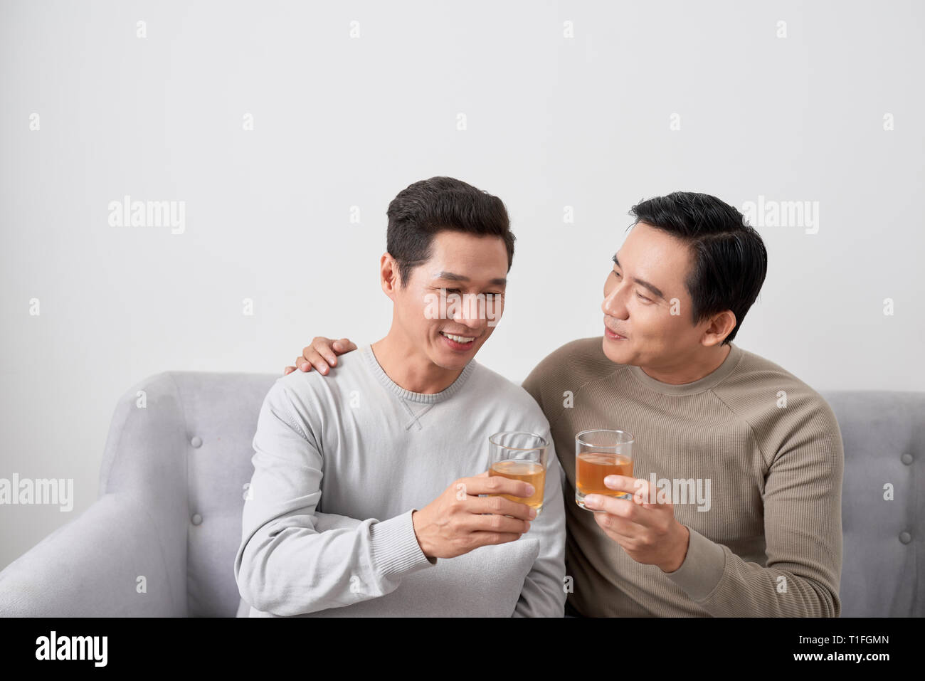 Men talk concept. Two young male friend gathering, chatting and eating at home. Stock Photo