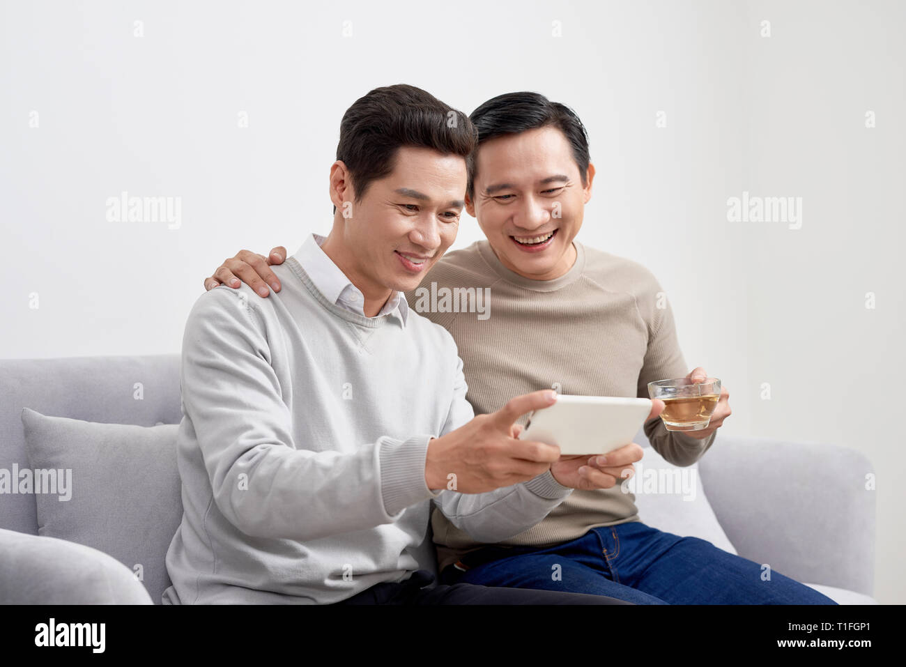 Cheerful young men dressed in casual wear smiling at camera while making selfie photo on front camera Stock Photo