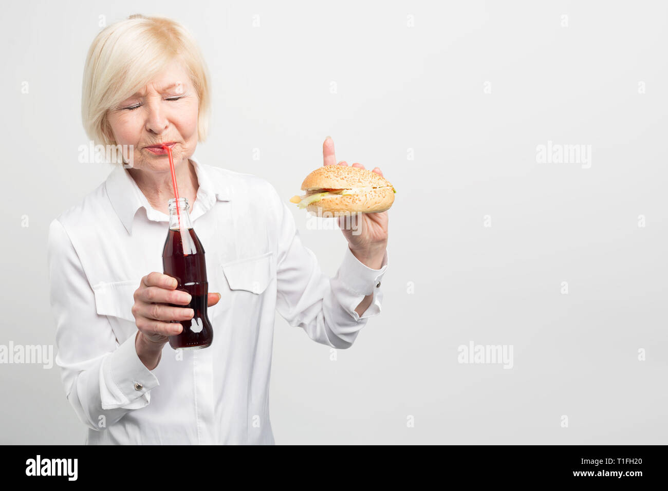 Download this stock image: A picture of old woman tasting coca cola. and ea...