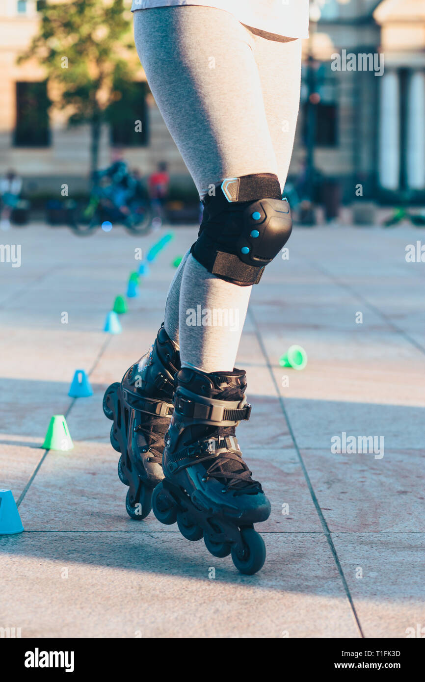 Young girl training the riding on roller skates. Closeup of female legs