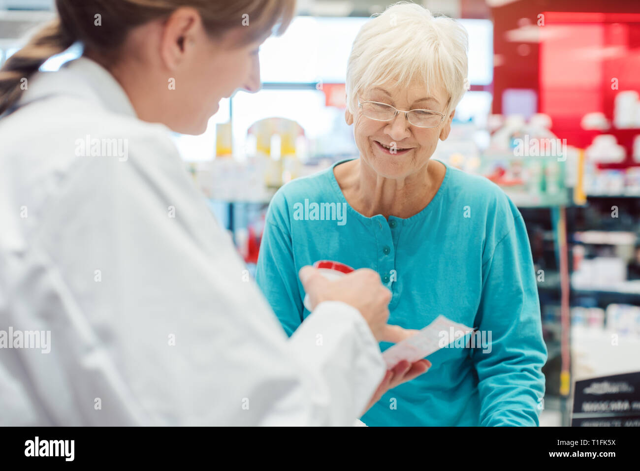 Senior woman in pharmacy talking to the chemist or pharmacist Stock Photo