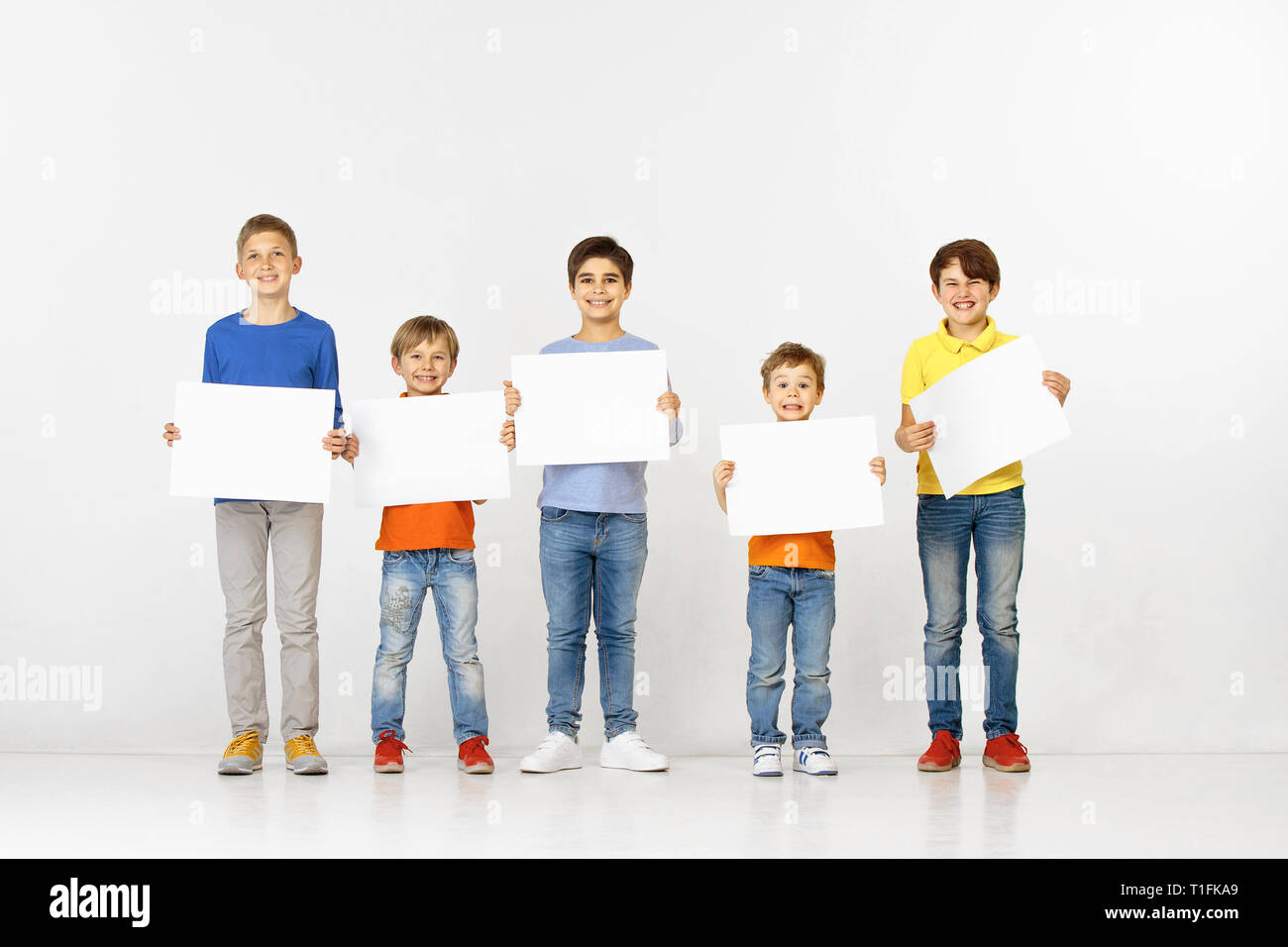 Group of happy children with a white empty banners isolated in light ...